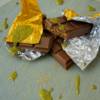 Dubai Chocolate bar infused with Albino Steel Magnolia mushrooms, wrapped in gold foil, with pistachio cream layers and saffron garnish, displayed on a marble surface with rose petals and incense.